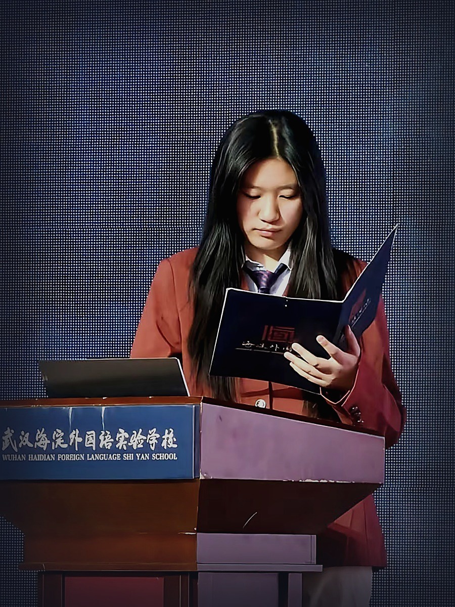 Linna Huang speaking at a podium on stage